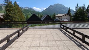 Eine Terrasse mit Blick auf Berge, Holzwertungen und Gebäude im Hintergrund.