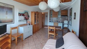 Un soggiorno accogliente con un divano, sedie in legno, una TV e un quadro appeso al muro.