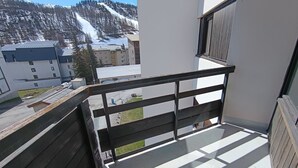 Un balcone con vista su una montagna innevata e degli edifici.