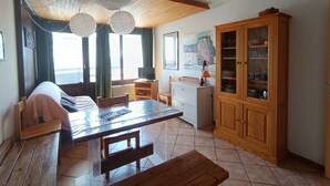 Una camera accogliente con un tavolo da pranzo in legno, un divano, un armadio e una finestra con tende.