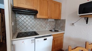A compact kitchen with wooden cabinets, a built-in stove, a sink, and a refrigerator. - Ski-in studio with private parking and pets allowed (Montgenèvre)