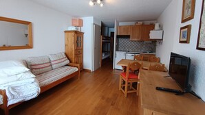 A compact living space with a bed, a wooden dining table with chairs, a kitchenette, and a television. - Ski-in studio with private parking and pets allowed (Montgenèvre)