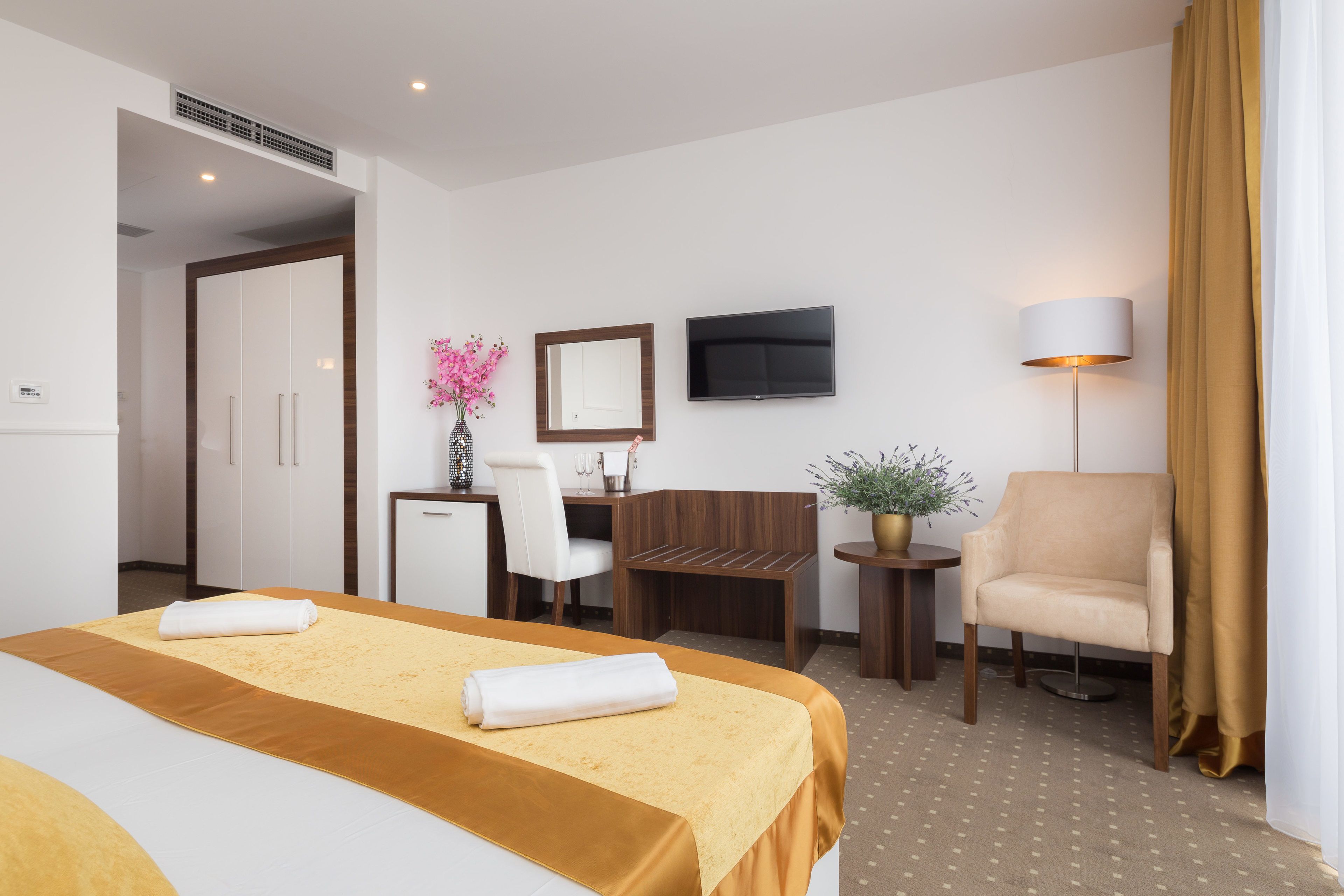 Ein Hotelzimmer mit Bett, Schreibtisch, Stuhl, Fernseher und Lampe.