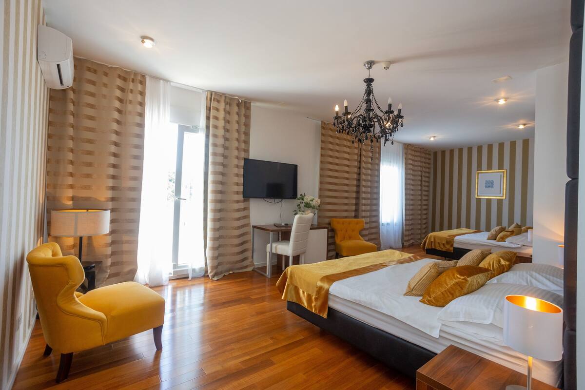 A hotel room with a large bed, a desk, a chair, and a TV.