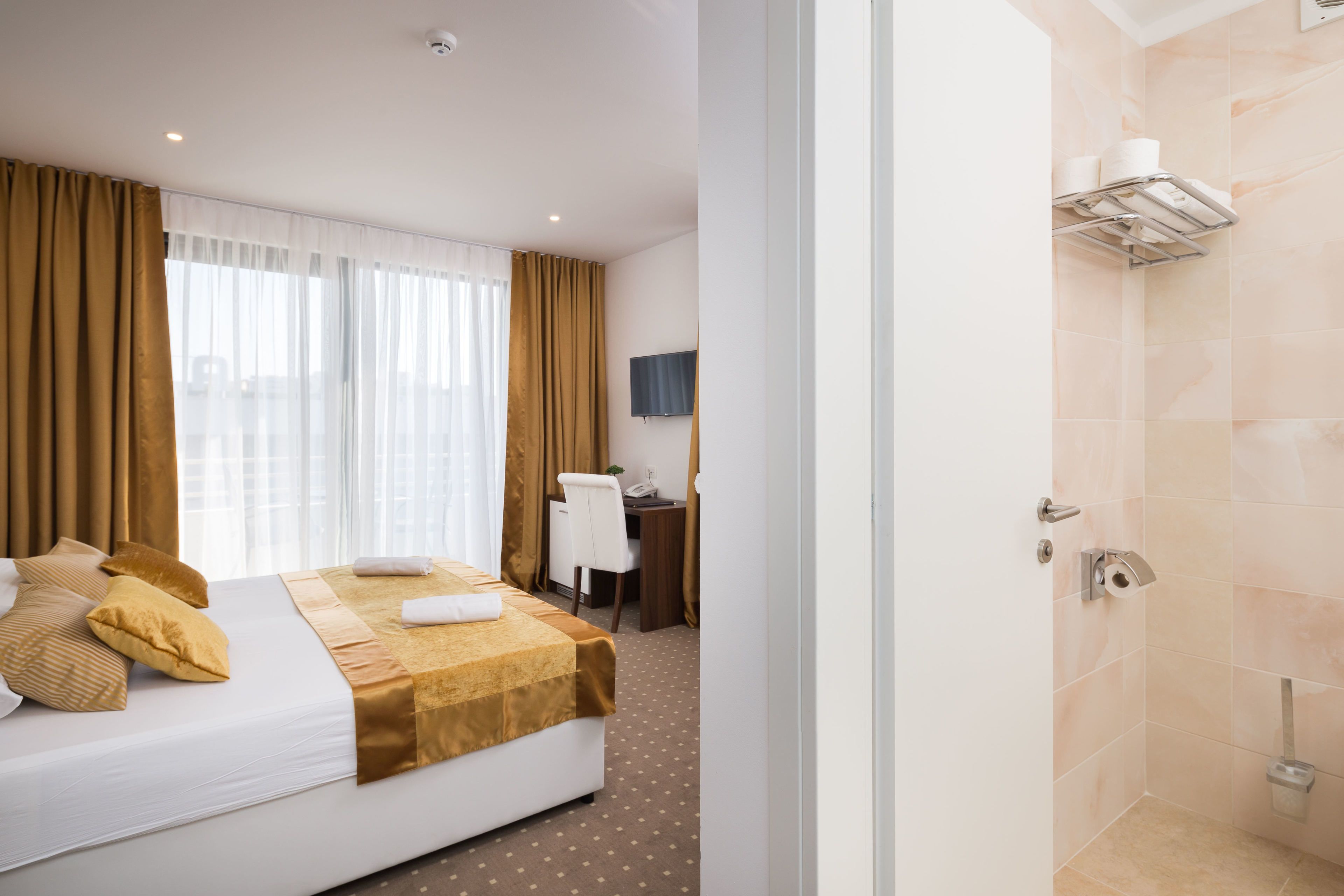 Une chambre d’hôtel équipée d’un lit, d’un bureau, d’une chaise, d’une télévision et d’un espace douche.