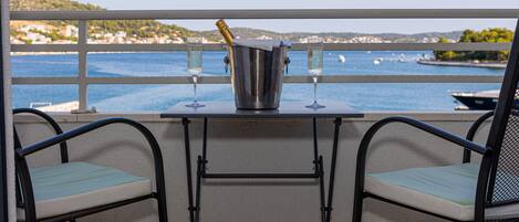A balcony with a table, two chairs, a champagne bucket, and two glasses.