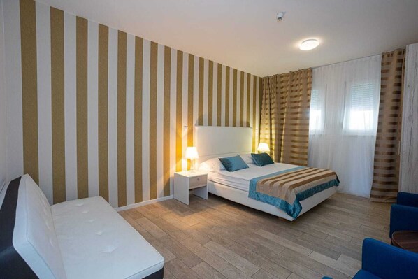A hotel room with a bed, bedside tables, a chair, and striped walls. - Hotel Perla (Rogoznica)