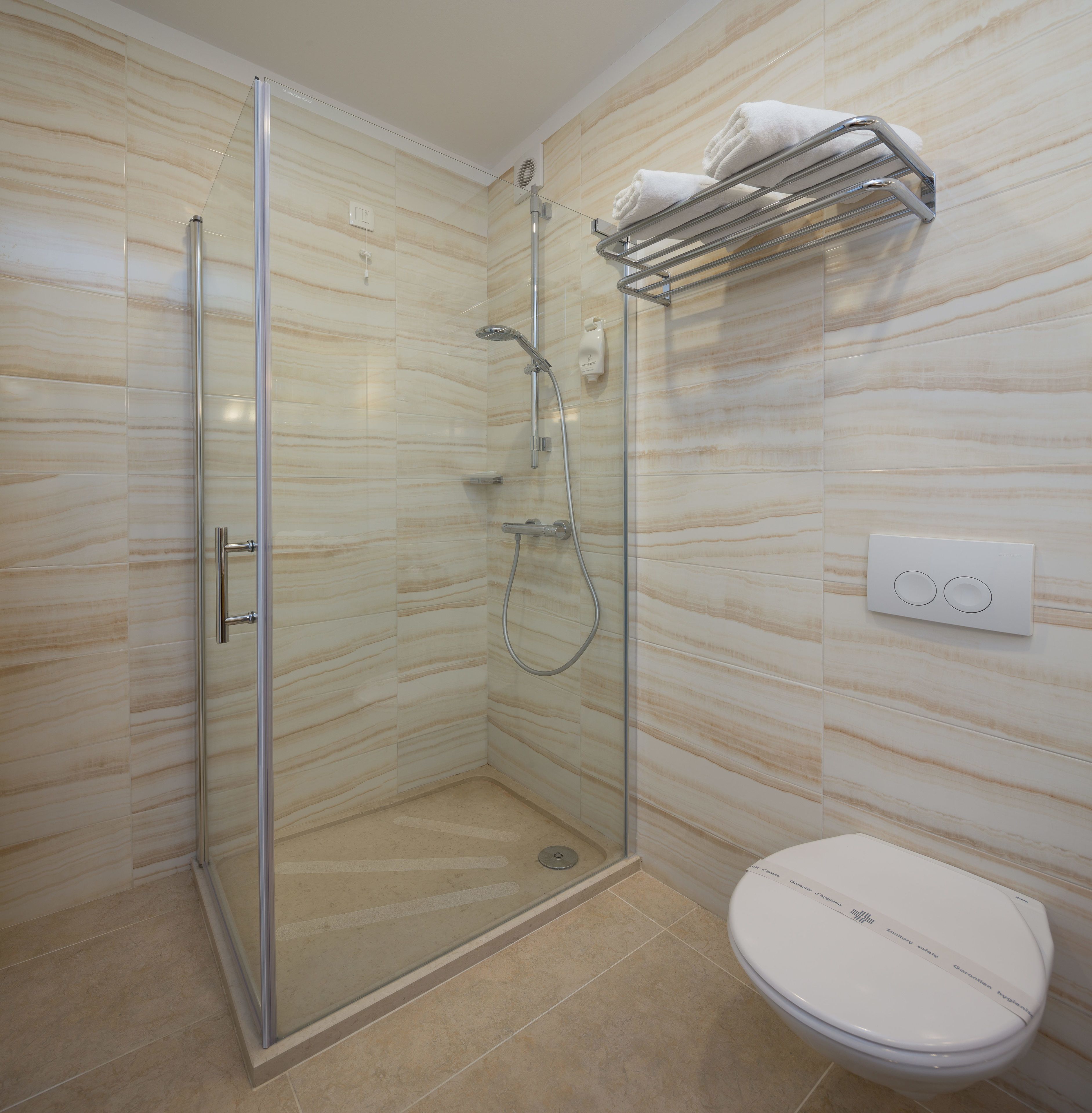 Un baño moderno con cabina de ducha de vidrio, inodoro y toallero.