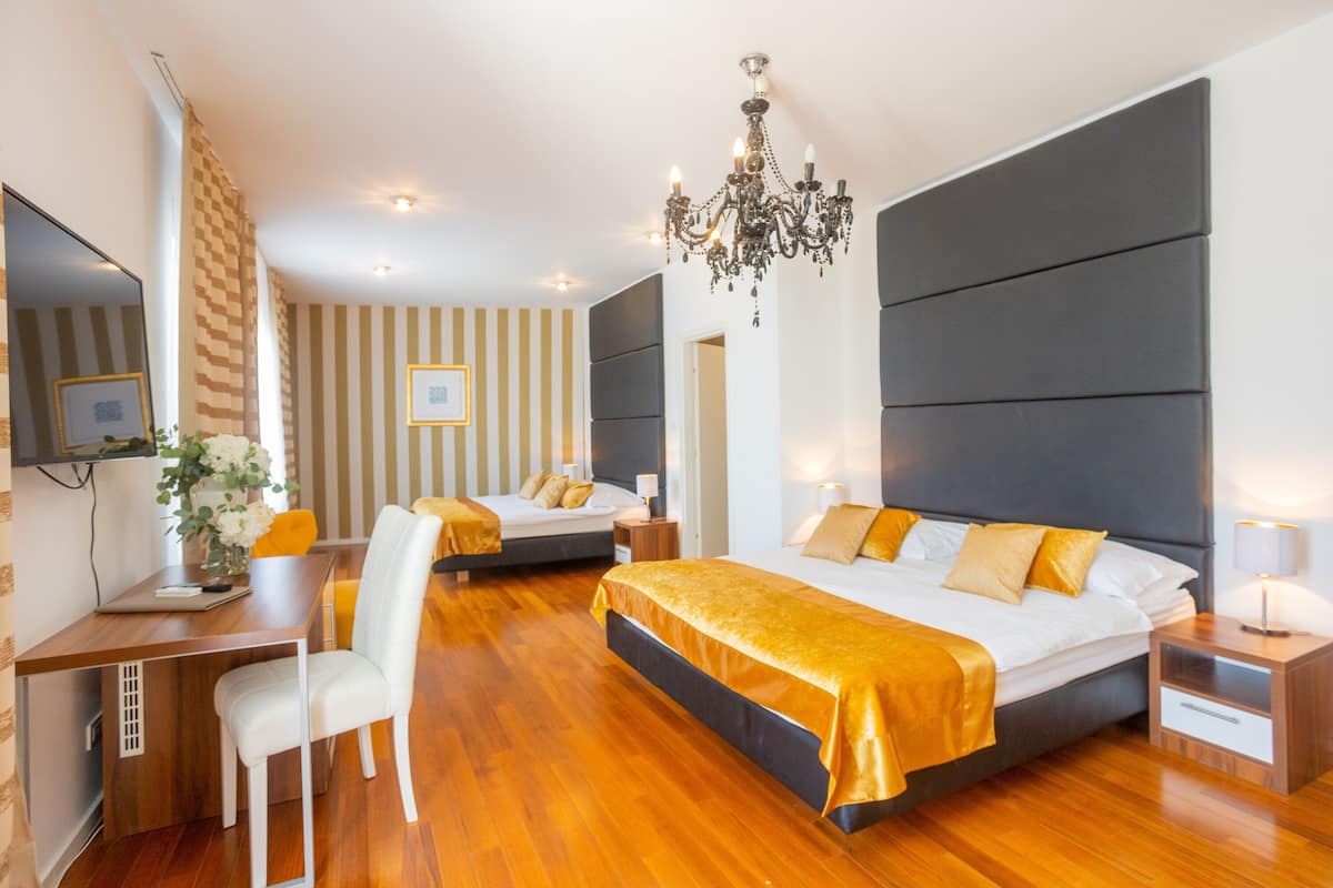 A modern hotel room with a large bed, a desk, and a chair. There is a chandelier hanging from the ceiling.