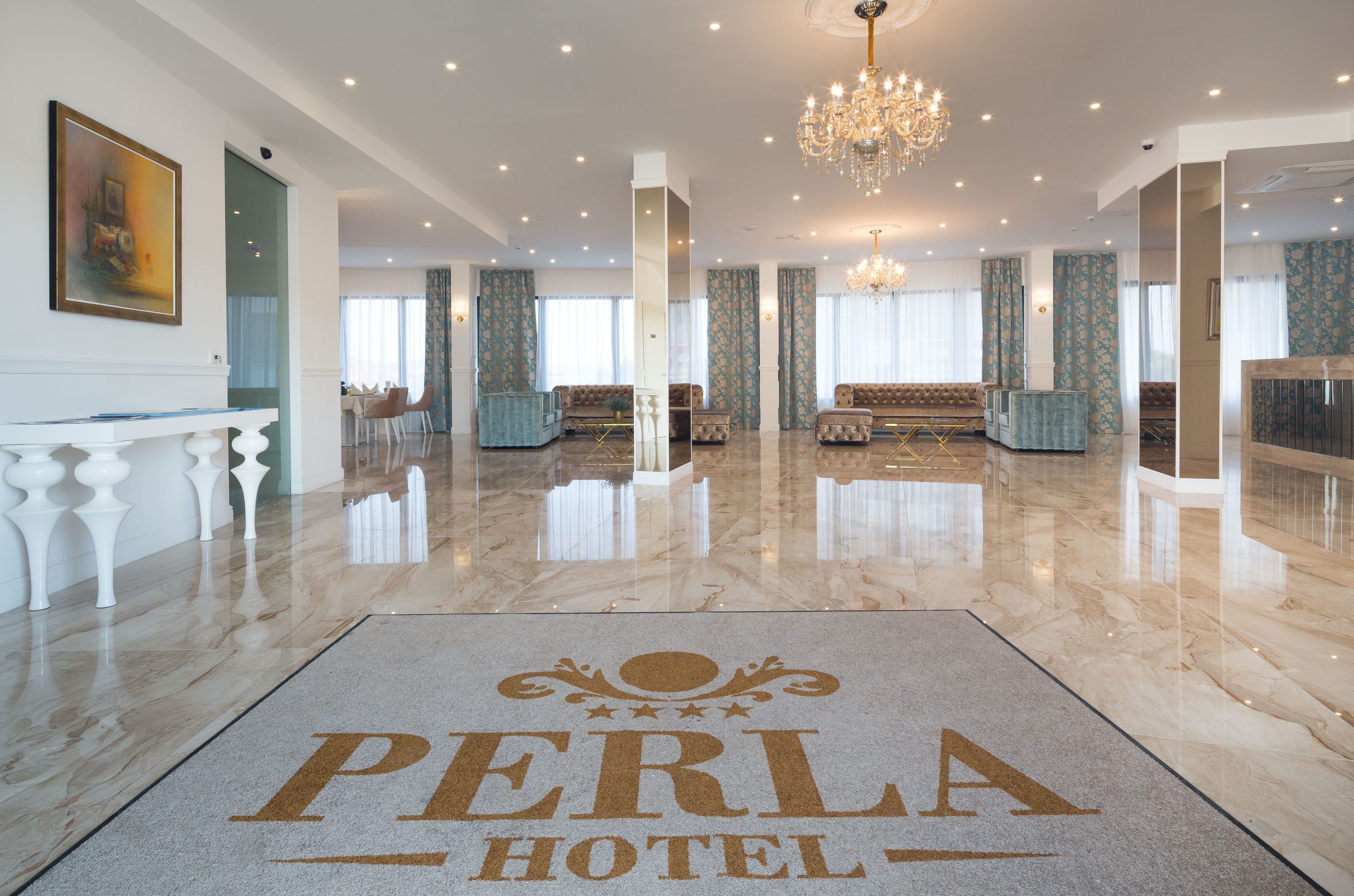 Un amplio vestíbulo de hotel con suelo de mármol, una araña y una recepción.