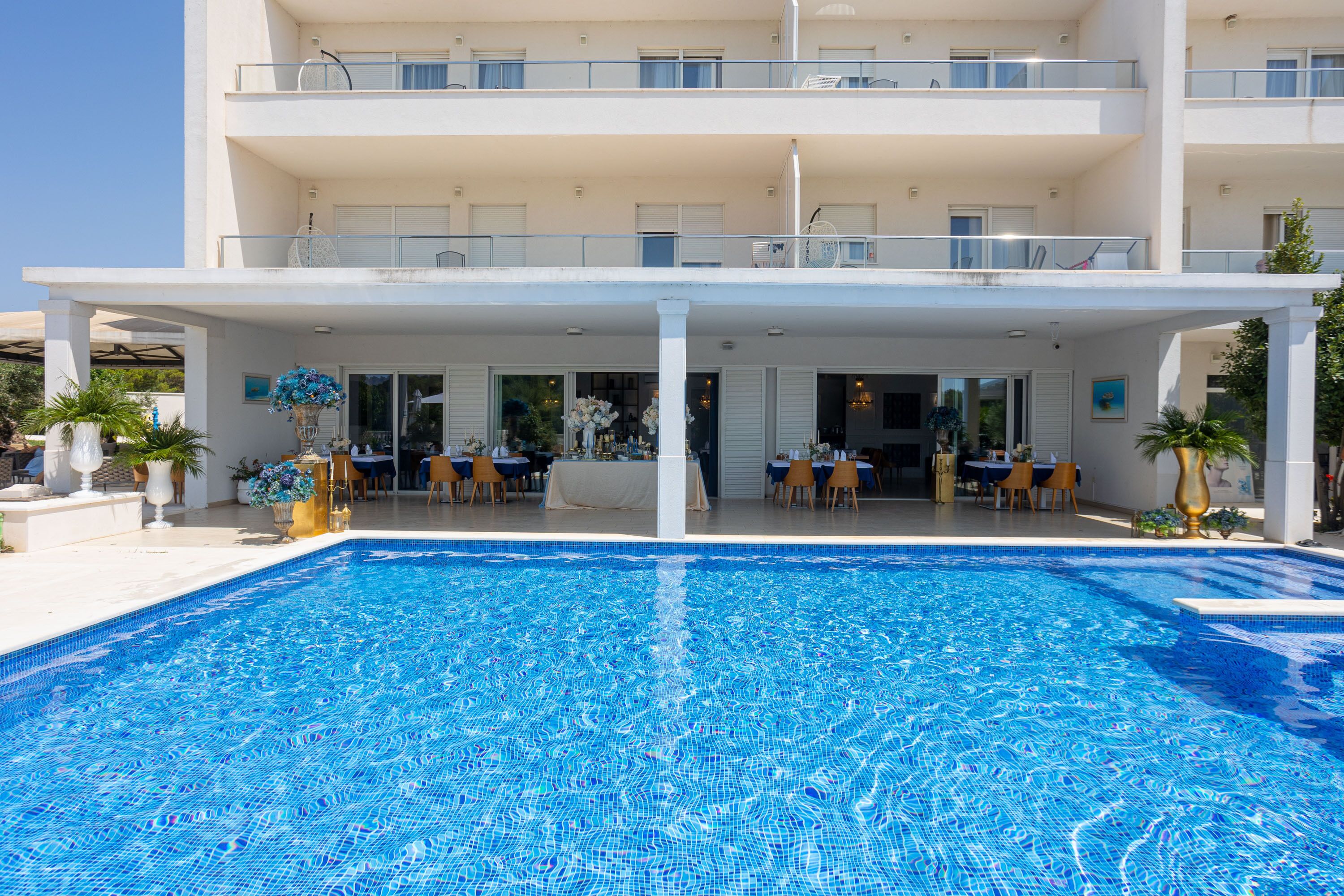 Un hotel con piscina, zona de estar al aire libre y varios balcones.
