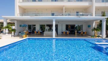 Un hotel con piscina, zona de estar al aire libre y varios balcones.