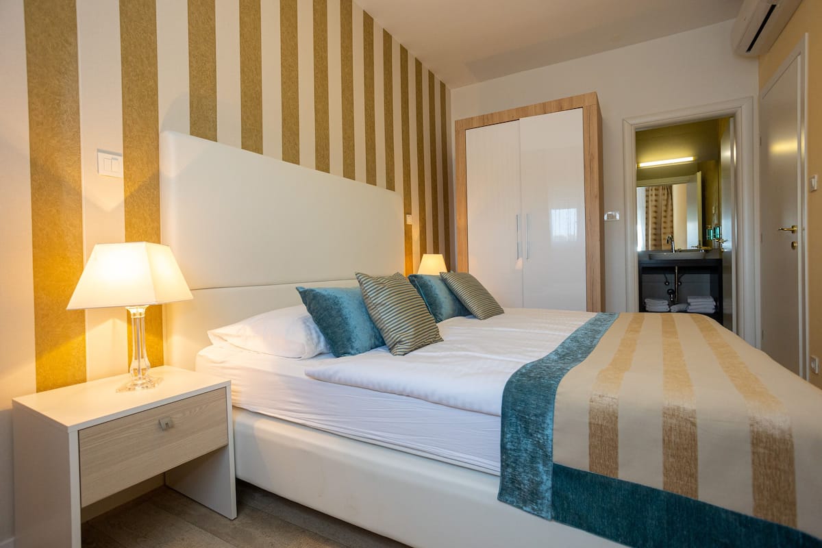 A neatly made bed with a striped blanket, a bedside lamp, and a nightstand with a drawer.