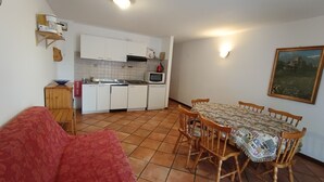 A compact living space with a kitchenette, a dining table with chairs, a red sofa, and a painting on the wall. - Apartment centrally located near slopes, pets allowed, parking included (Montgenèvre)