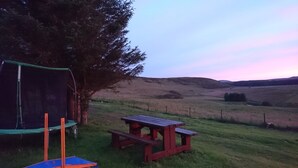 Eine Wiese mit Picknicktisch und Trampolin.