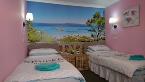 Ein Schlafzimmer mit zwei Betten, einem Wandbild mit Strandmotiv und einem Blumenbild.
