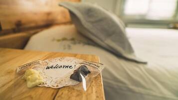 A wooden table with a welcome mat and a small package labeled "Patagonia" on a bed with a white sheet and a pillow.