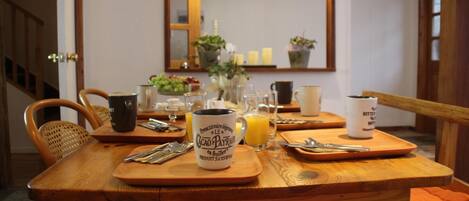 A wooden dining table with cutlery, a mug, and a glass of orange juice.