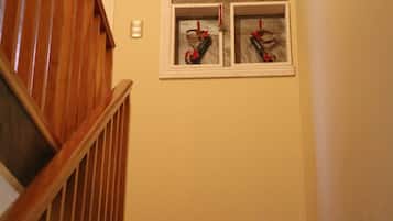 Una escalera de madera que lleva a un rellano con una puerta blanca y un ventanal con cuatro objetos enmarcados.