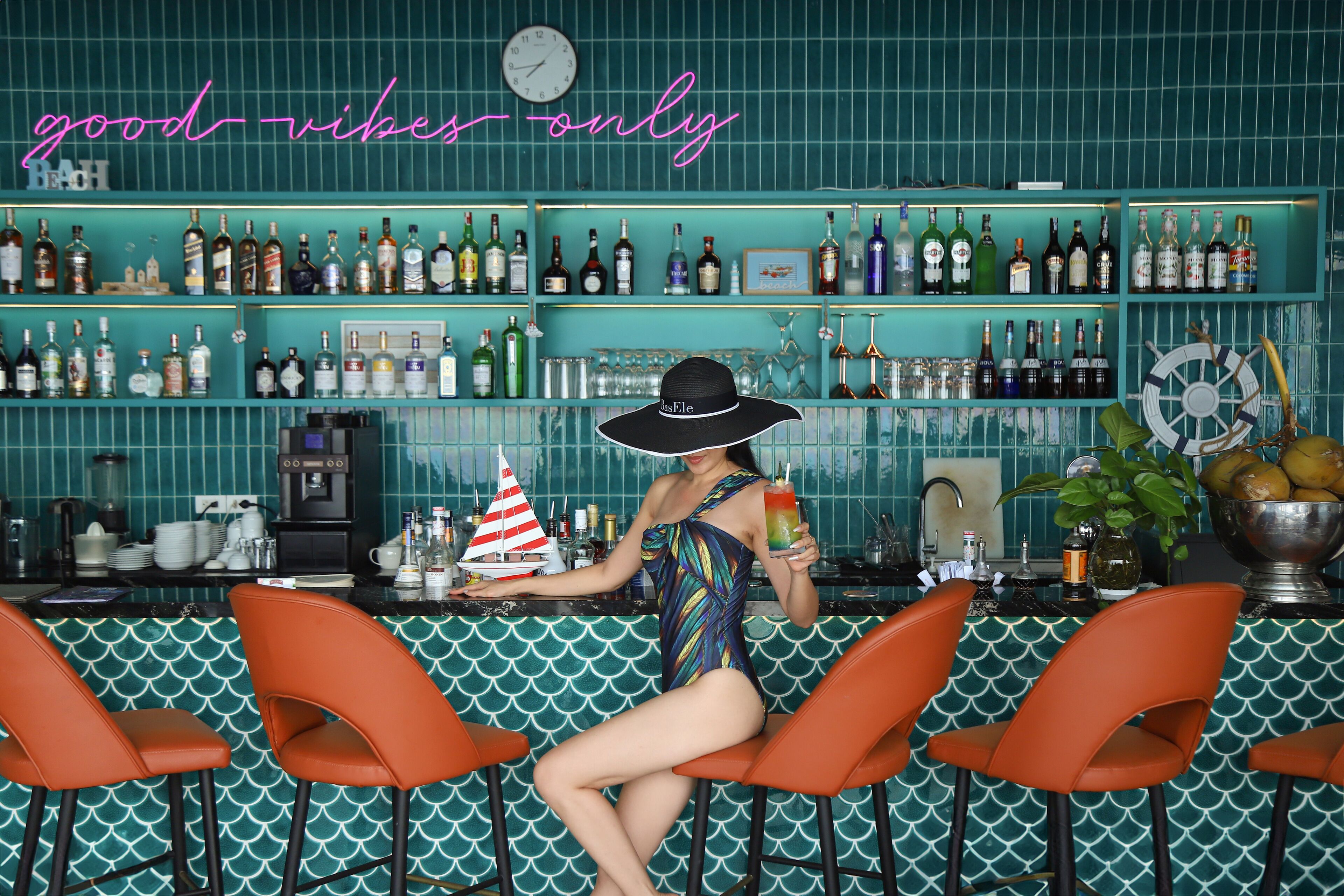A bar with a neon sign reading "good vibes only" and a variety of liquor bottles on shelves.