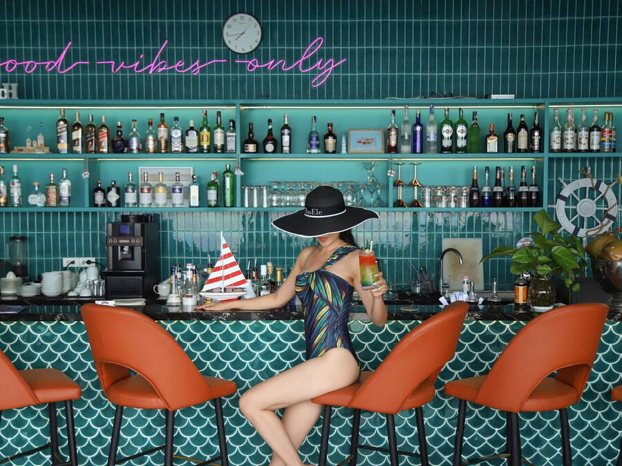 A bar with a neon sign reading "good vibes only" and a variety of liquor bottles on shelves.