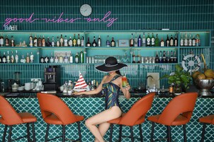 A bar with a neon sign reading "good vibes only" and a variety of liquor bottles on shelves.