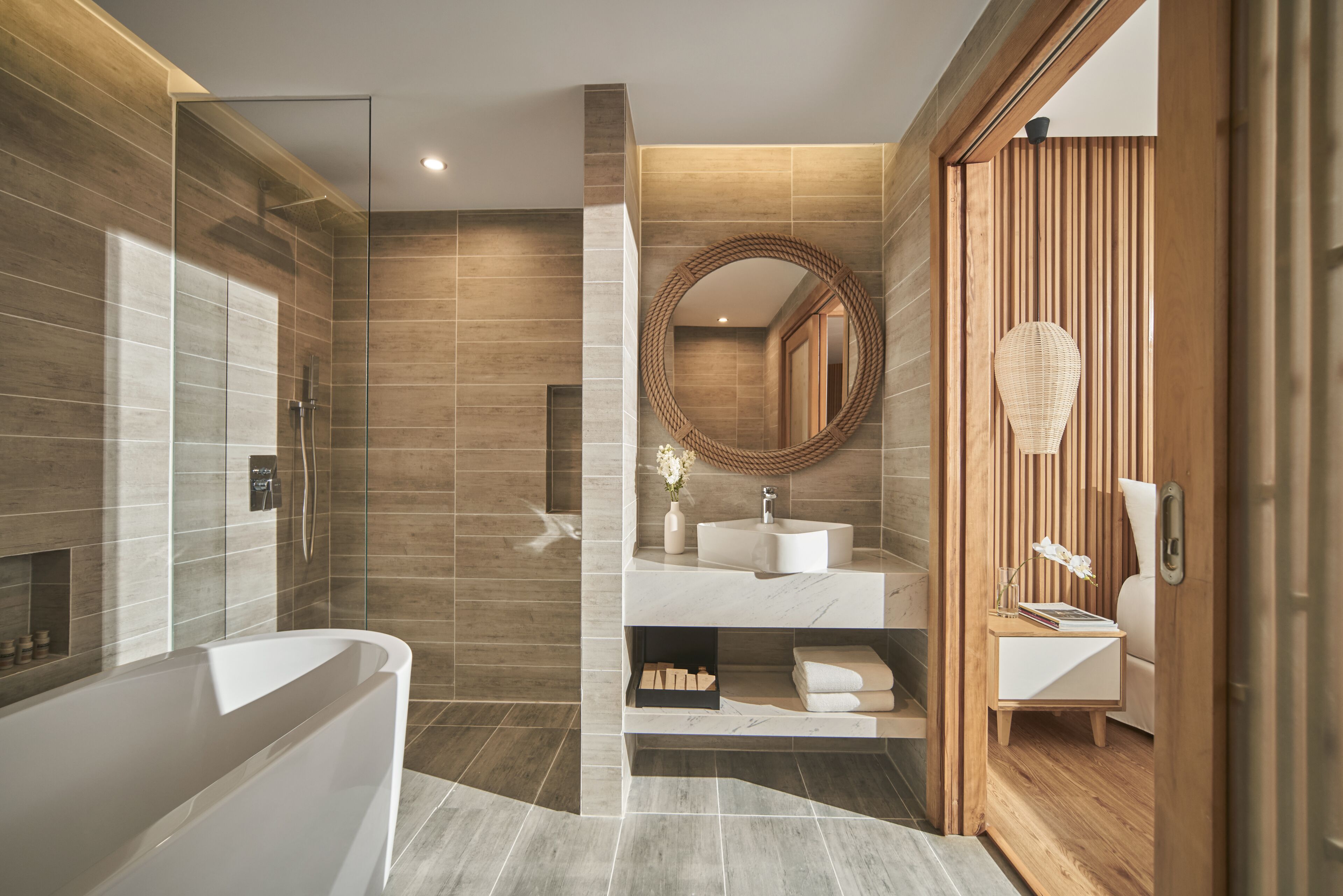 A modern bathroom with a glass-enclosed shower, a freestanding bathtub, and a vanity with a round mirror.