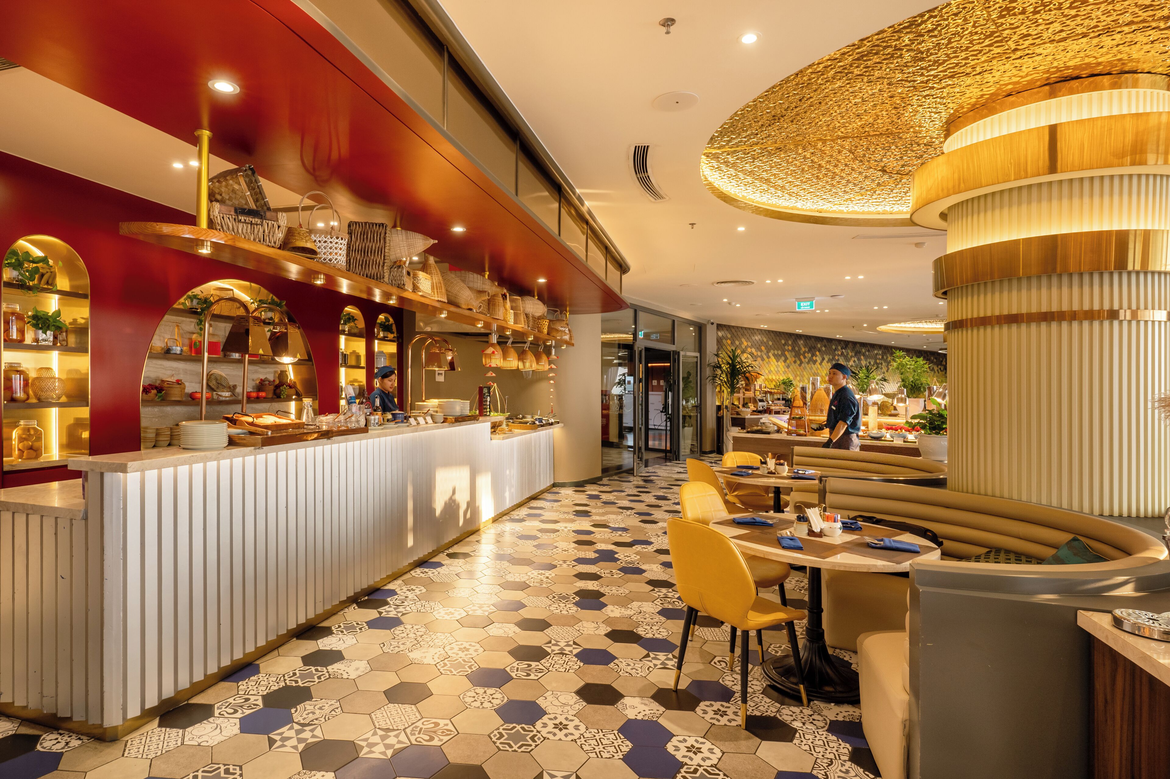 Un restaurante moderno con área de bar, suelo de patrón hexagonal y zona de estar con sillas amarillas.