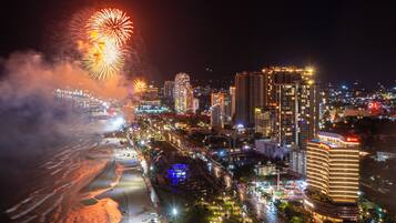 Un paysage urbain avec de hauts immeubles, une plage et des feux d’artifice.