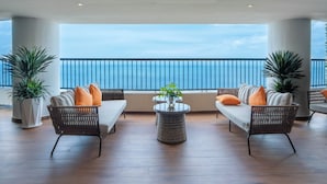 A balcony with two wicker sofas, a round table, and potted plants. - Vias Hotel Vung Tau (Ho Chi Minh City)