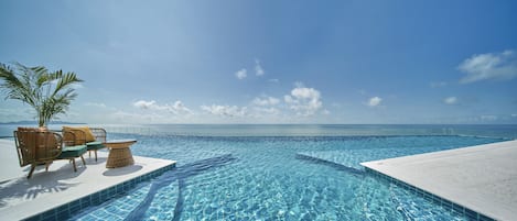 Una piscina al aire libre, sillones reclinables de piscina