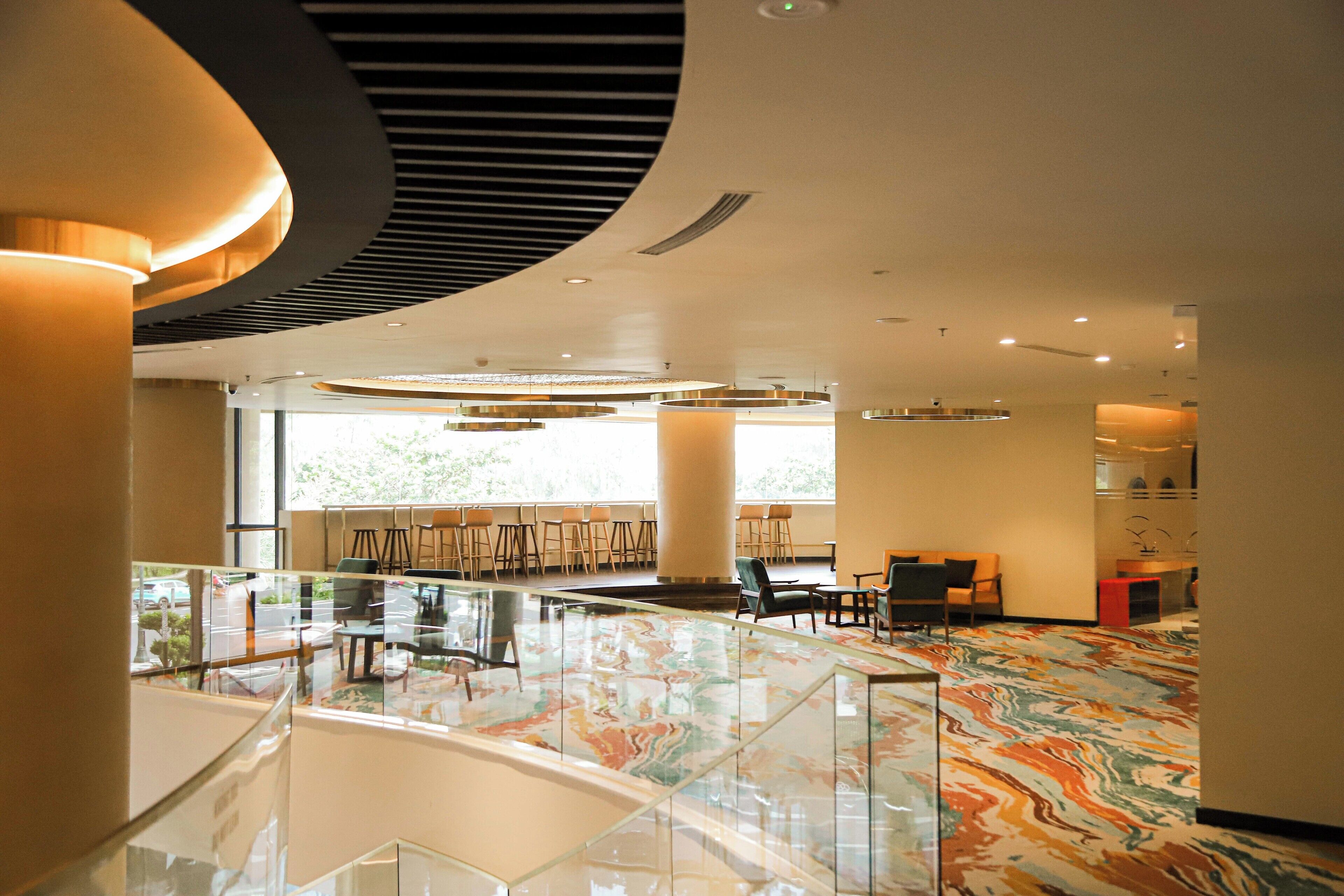 A spacious lobby with a glass railing, a marble floor, and a seating area with chairs and tables.