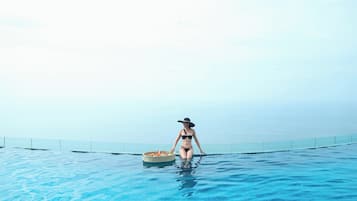Guests can enjoy a serene swim in the pool surrounded by a glass barrier with a clear view of the horizon.