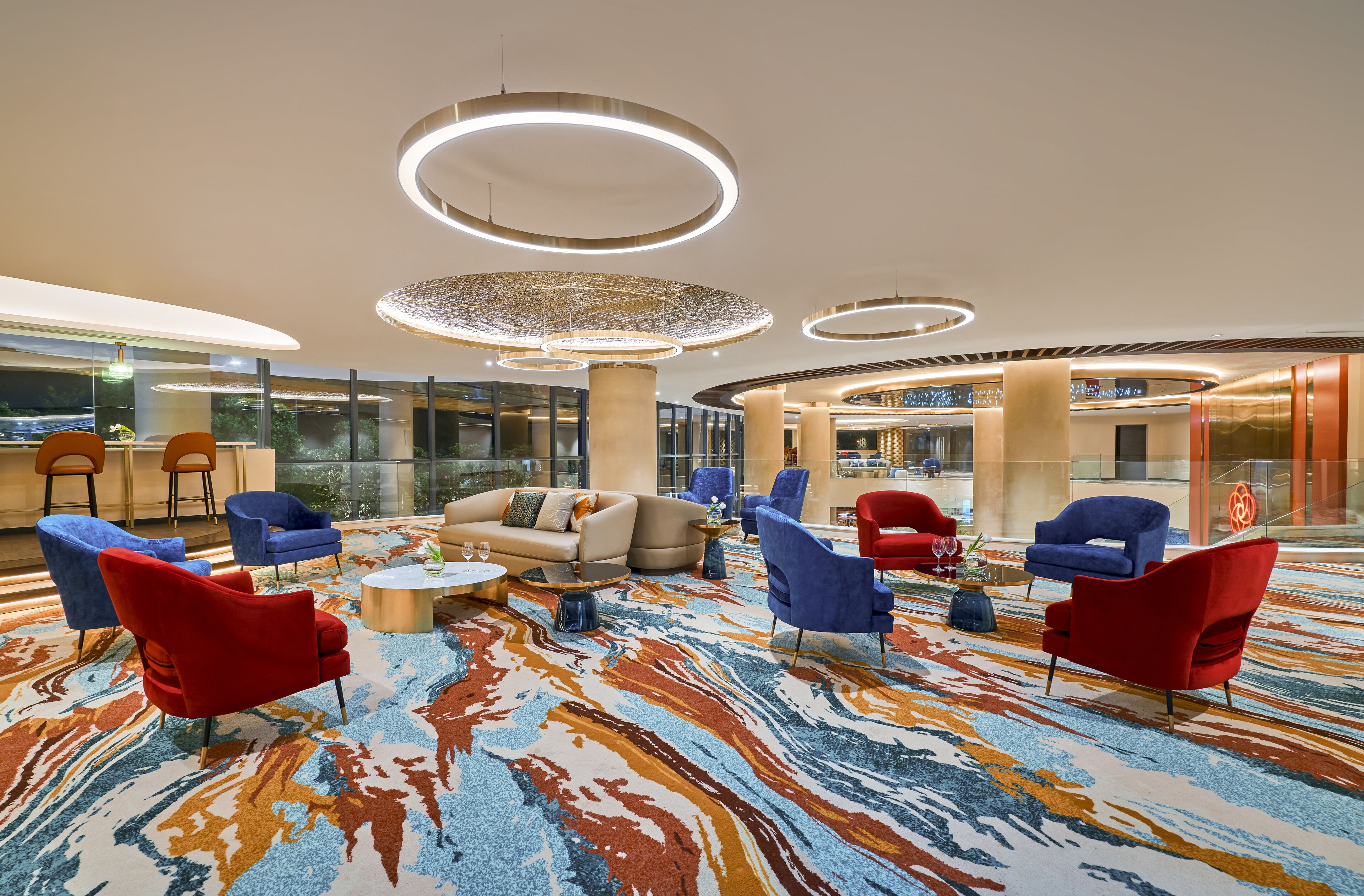A spacious lobby with modern seating, large windows, and a patterned carpet.