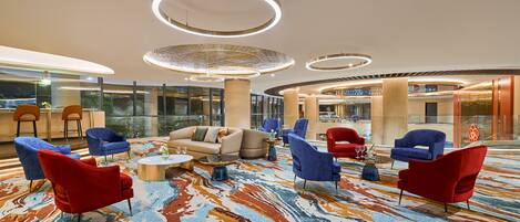 A spacious lobby with modern seating, large windows, and a patterned carpet.