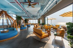 Um espaço amplo e interno com assentos, ventiladores de teto e grandes janelas.