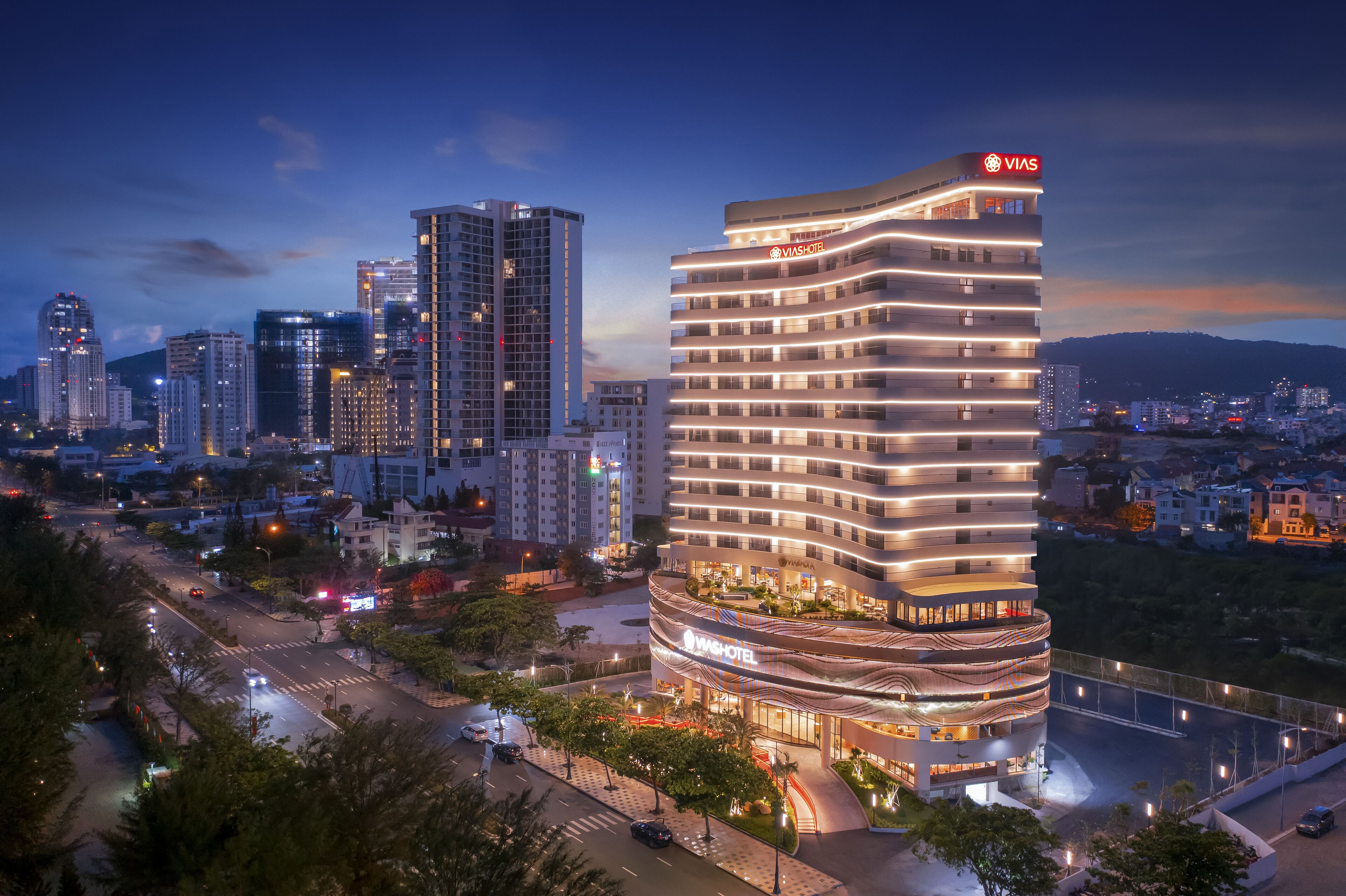 Un hôtel moderne à la façade incurvée, doté de plusieurs étages et d’une enseigne bien visible indiquant « VIA HOTEL ».