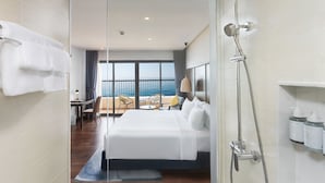 A modern hotel room with a large bed, a shower, a view of the ocean, and a balcony with seating. - Vias Hotel Vung Tau (Ho Chi Minh City)
