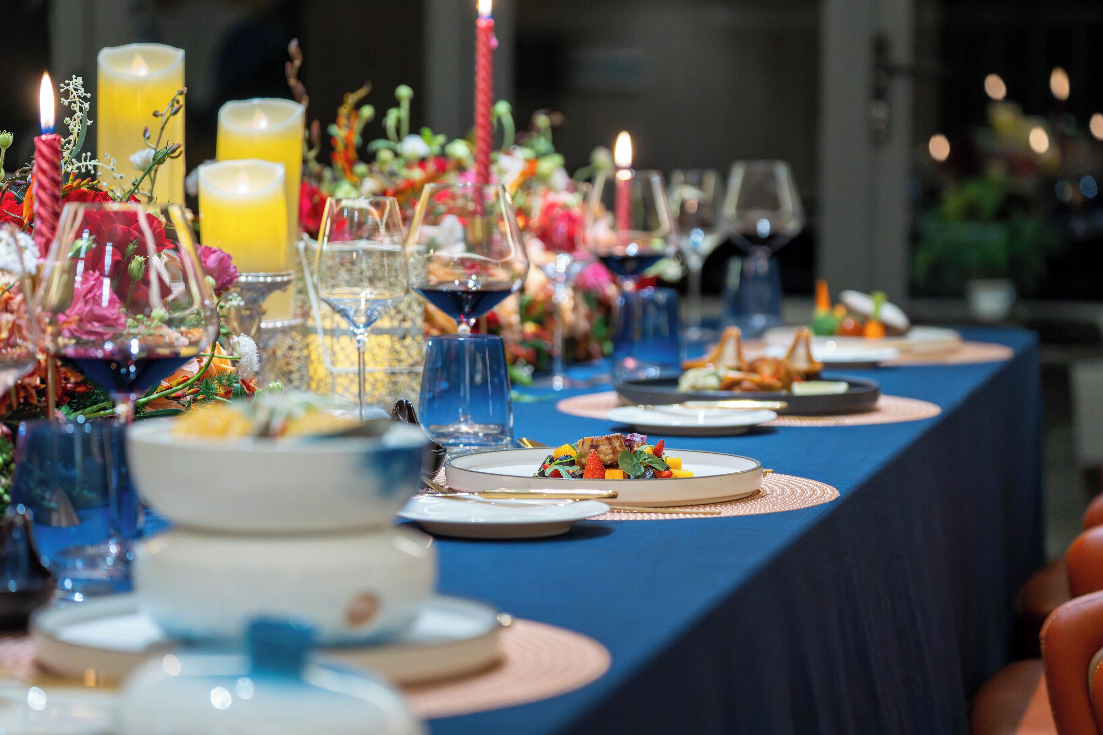 Mesa servida con platos, vasos y velas, indicando una disposición formal para cenar.