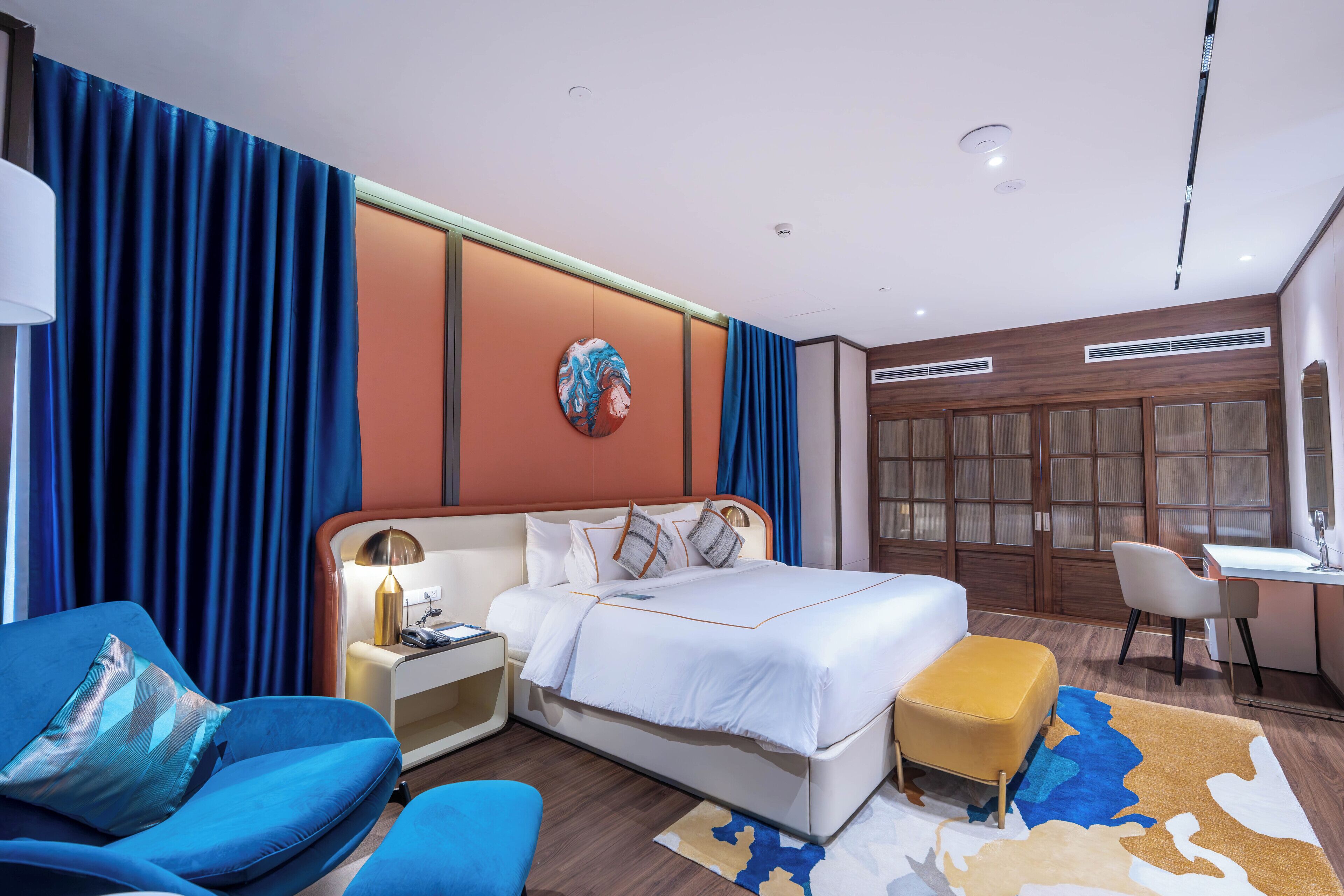 Una habitación de hotel moderna con una cama grande, un escritorio, una silla y un sofá.