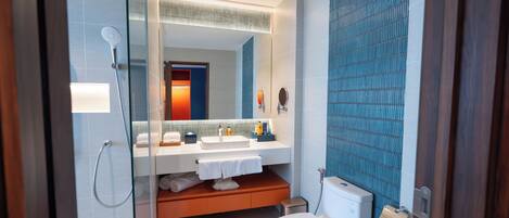 Un baño moderno con ducha de vidrio, inodoro blanco y lavamanos con espejo.