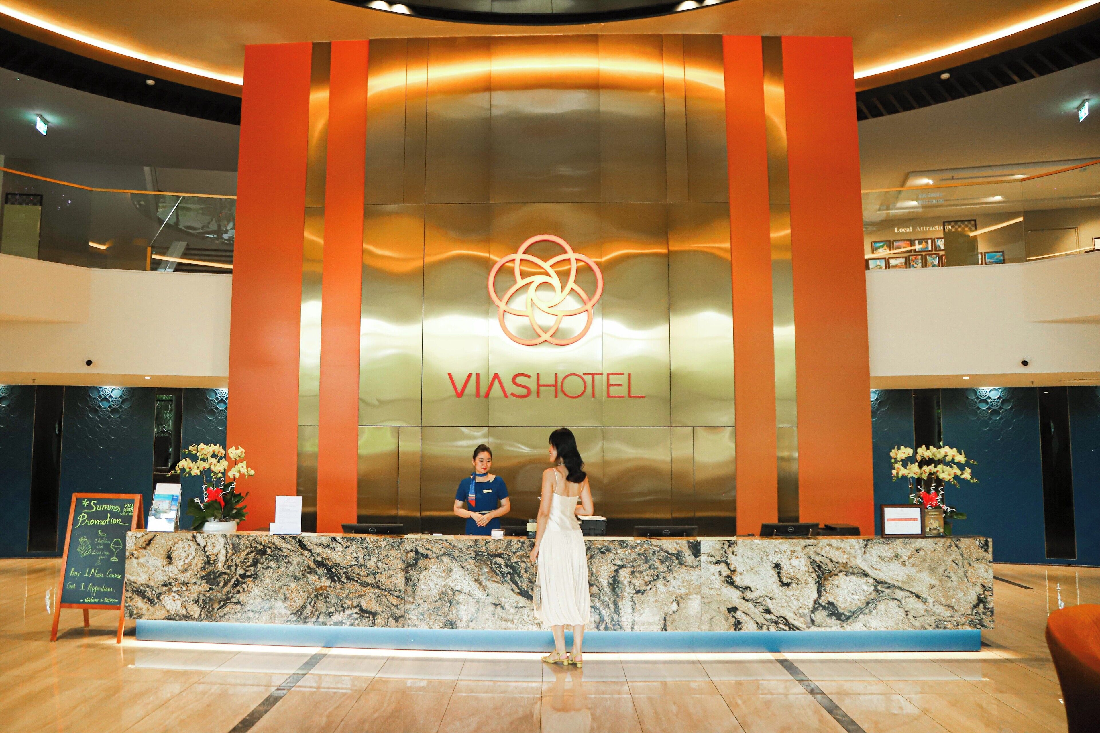 A reception desk with a marble top, a receptionist, and a guest standing.