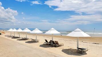 A beach with white umbrellas and lounge chairs.