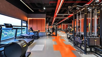Un gimnasio con equipo de ejercicio, una cinta de correr y vistas al exterior.