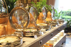 A buffet with various food items and a variety of dishes displayed in metal bowls and baskets.