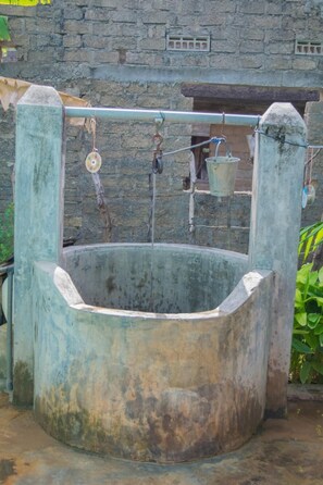 A large, circular stone well with a metal structure inside, surrounded by a stone wall. - Nilaveli Beach Inn (Nilaveli)