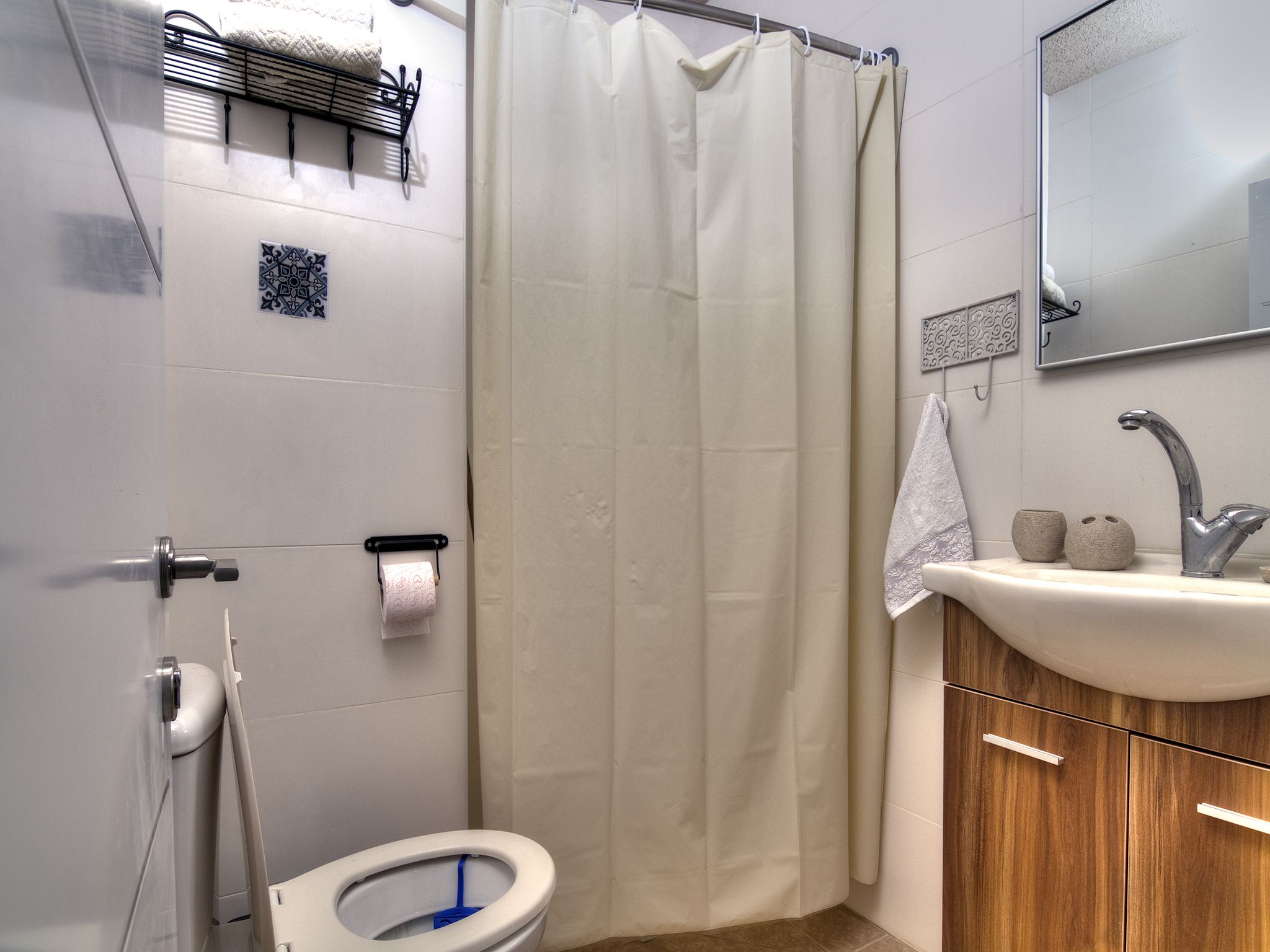 Une salle de bain équipée de toilettes, d’un lavabo, d’un rideau de douche et d’un miroir.