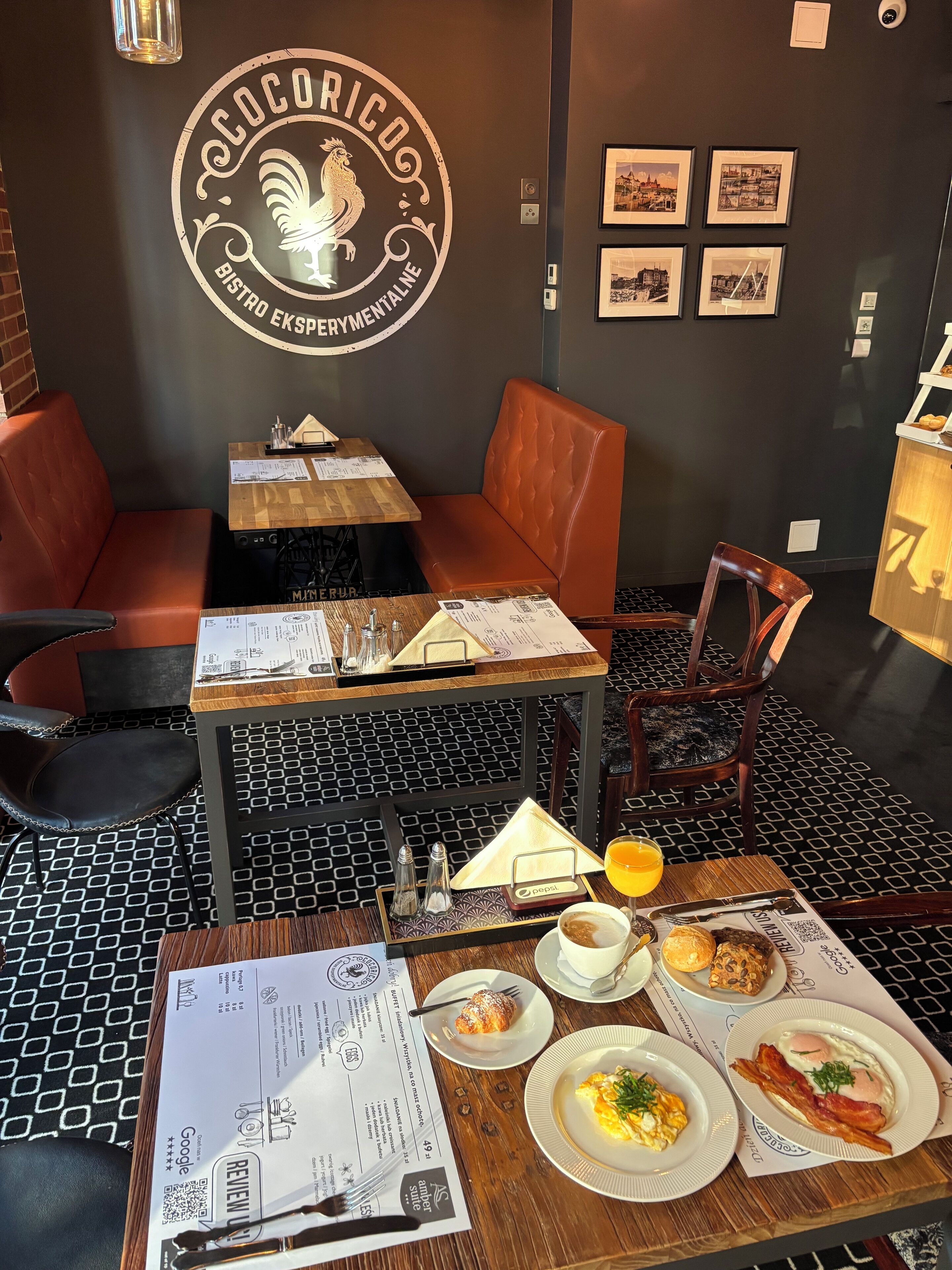 A restaurant interior with a black and white checkered floor, wooden tables, and orange cushioned seating.