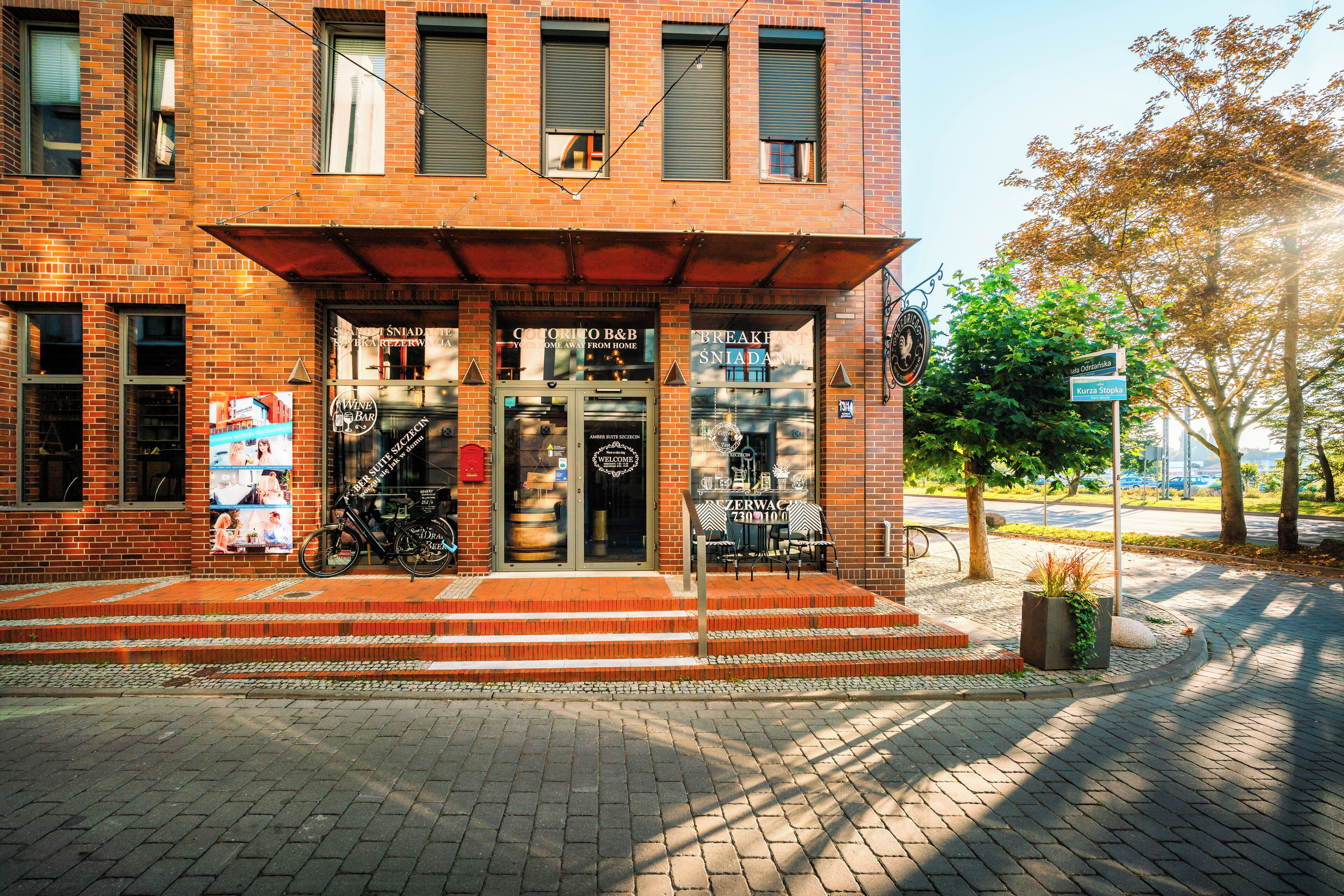 Ein Backsteinhaus mit Schaufenster, Außenbestuhlung und einem Fahrrad vor der Tür.
