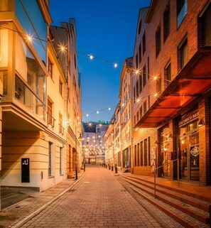 A street lined with buildings, some with visible signage, and string lights overhead. - Amber Suite Szczecin Adults Only (Szczecin)